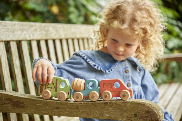 Kind speelt buiten met TickiT gekleurde houten voertuigen